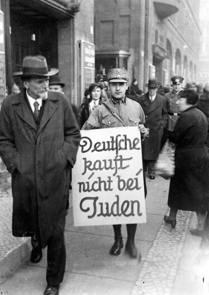 Pripadnik SA u aprilu 1933. sa natpisom kojim se poziva na bojkot jevrejskih radnji u Berlinu