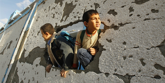 Palestinian schoolboys look through a hole at their damaged school in Gaza City on Saturday http://cnn.it/1k5mvkl