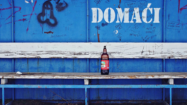 Flaša piva na klupi na fudbalskom terenu