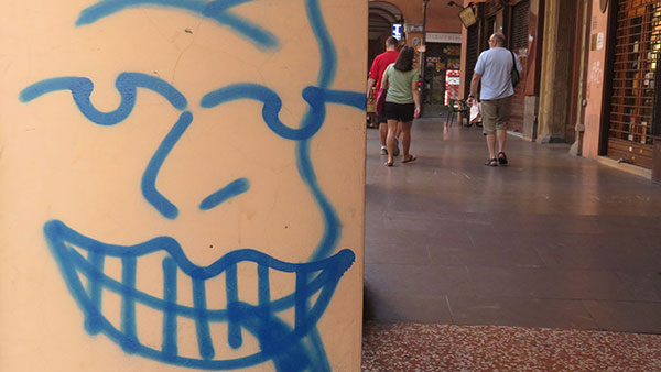 lice koje se smeje nacrtano na stubu u Bolonji