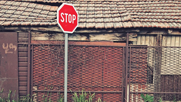 saobraćajni znak Stop ispred napuštene kuće