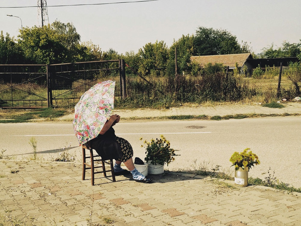 žena sa kišobranom prodaje cveće na ulici