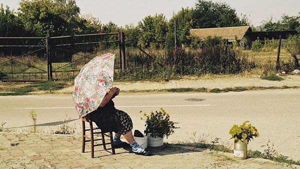 žena sa kišobranom prodaje cveće na ulici