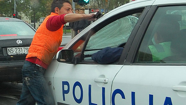 Čovek pere šoferšajbnu na policijskim kolima