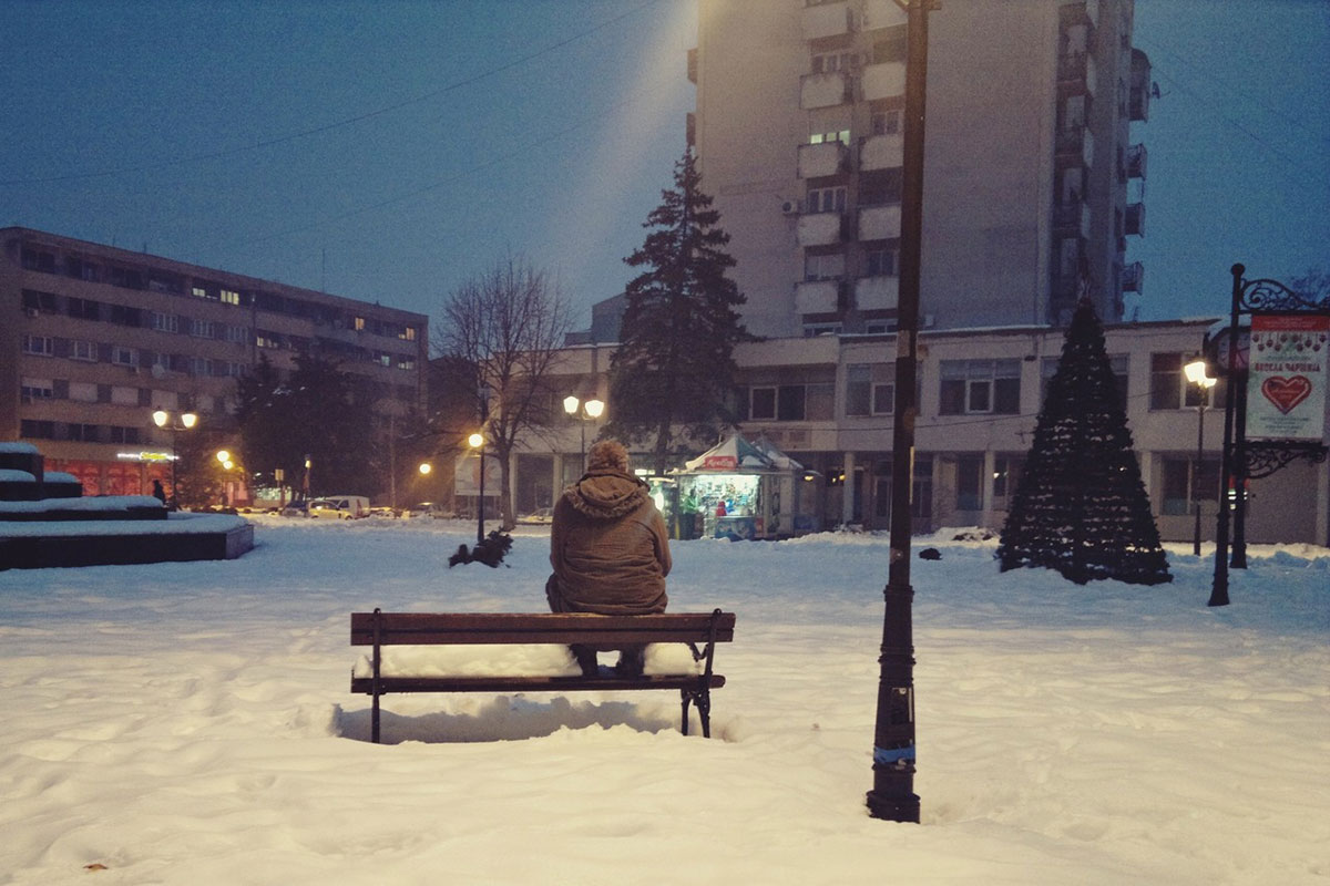 čovek sedi na klupi u parku