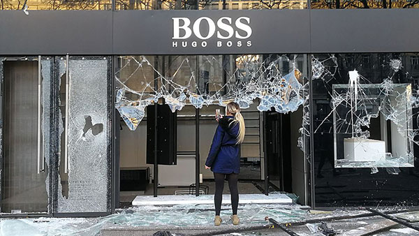 Žena fotografiše razbijeni izlog Hugo Boss radnje