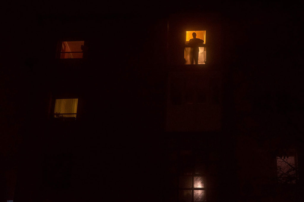 Čovek stoji  na balkonu u mraku