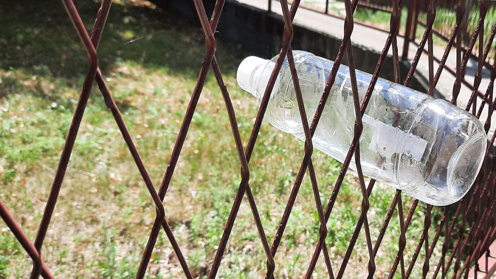 Prazna plastična flaša zakačena za školsku ogradu