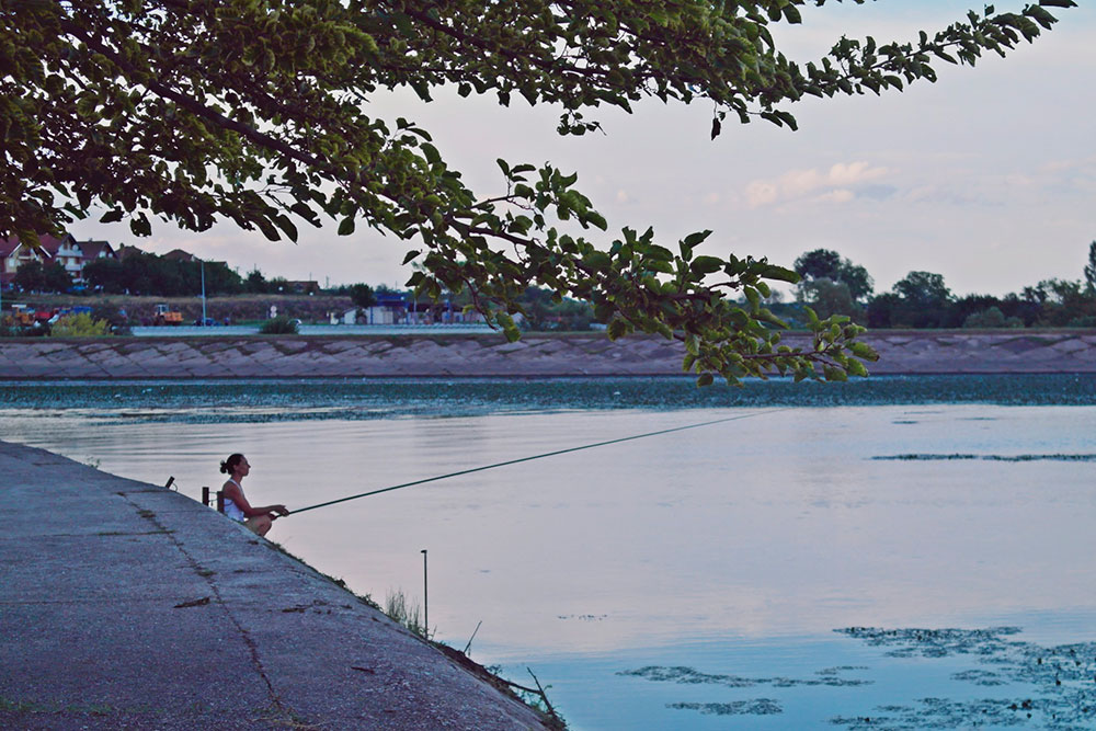 žena peca na obali reke