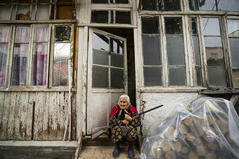 Starica sa puškom u krilu sedi ispred kuće u Azerbejdžanu